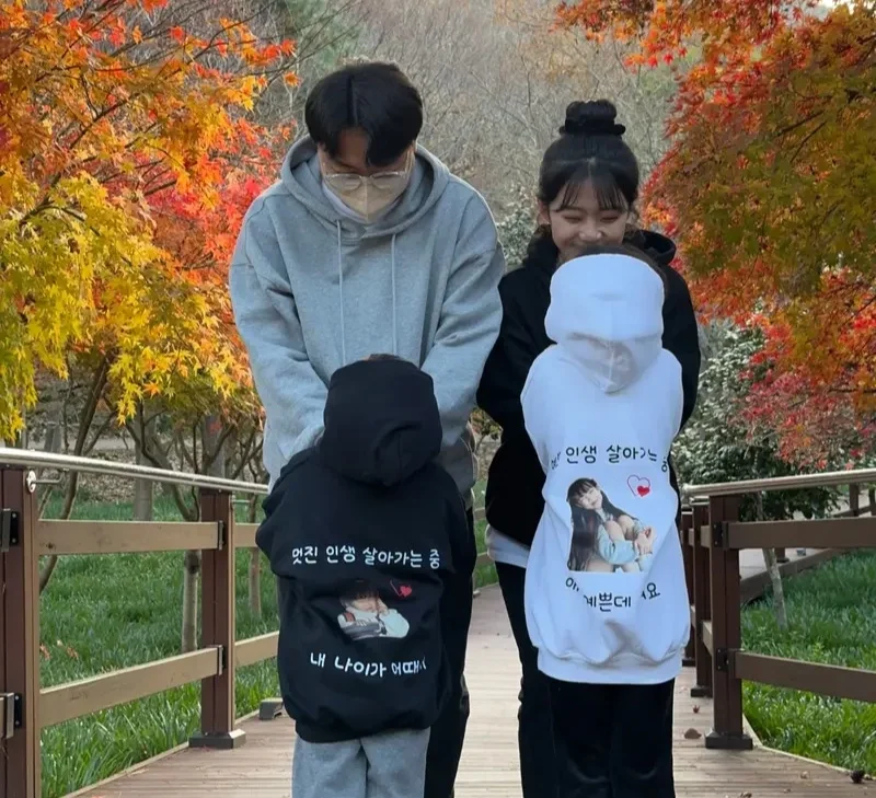 마플 가족 후드티 제작 – 가족사진과 문구를 등판에 프린팅한 블랙과 화이트 후드티를 맞춰 입은 가족의 가을 나들이 이미지